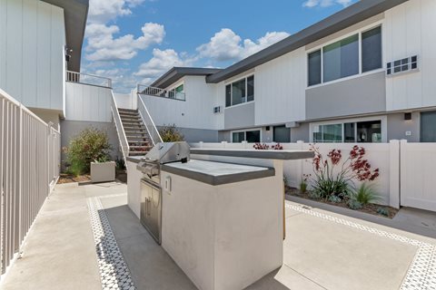 a barbecue grill sits in front of a building with a staircase